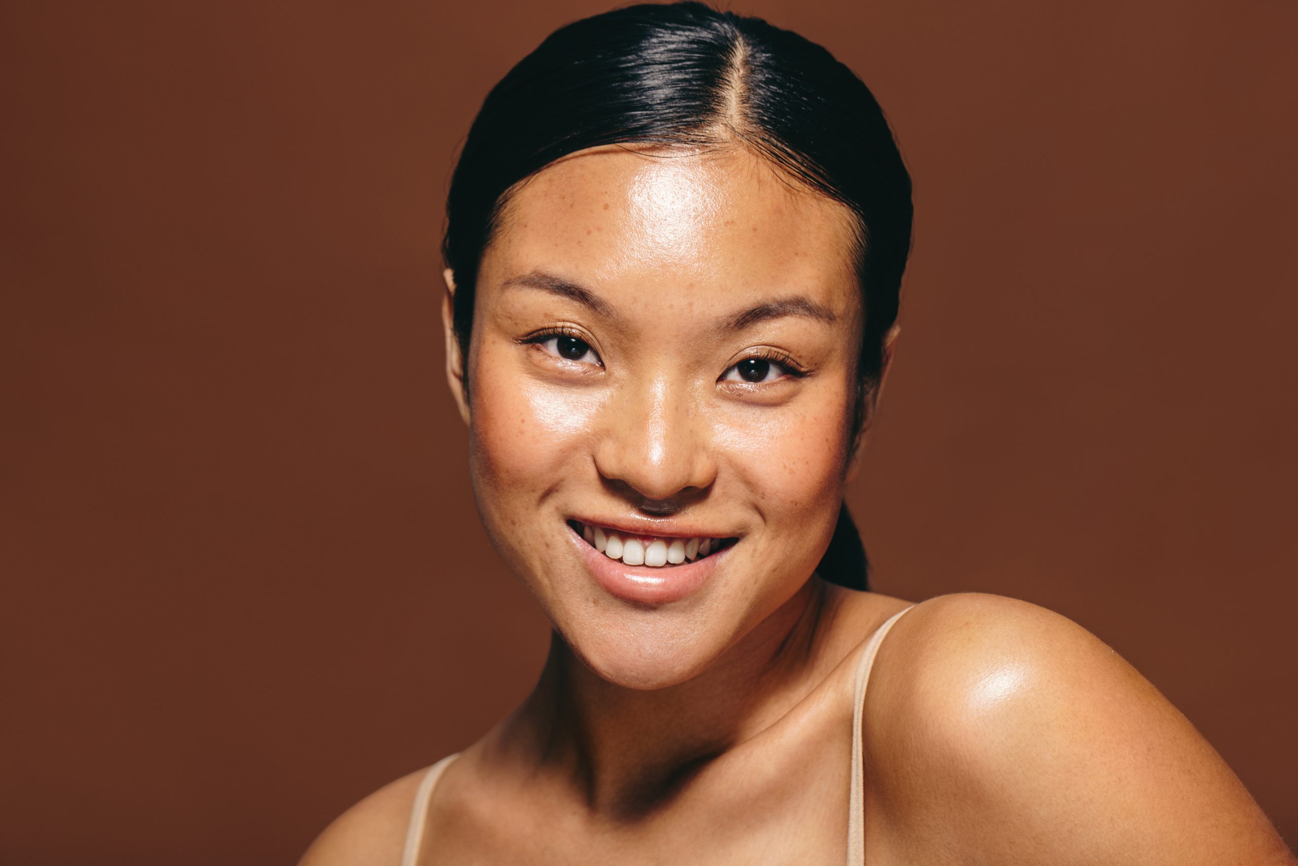 Portrait of a young woman in her 20’s smiling at the camera, she is radiating confidence and self-assurance. This beautiful woman has embraced a healthy skincare routine and is flaunting the flawless results.